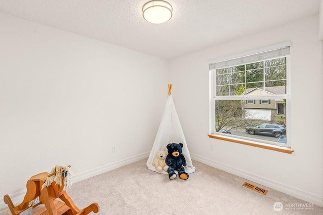 playroom featuring visible vents, a textured ceiling, baseboards, and carpet floors