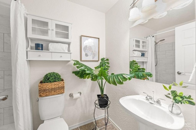 bathroom with curtained shower, toilet, baseboards, and a sink