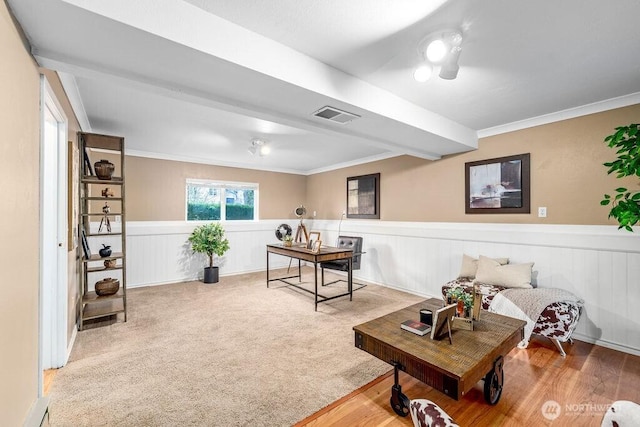 living room featuring a wainscoted wall, carpet, visible vents, and ornamental molding