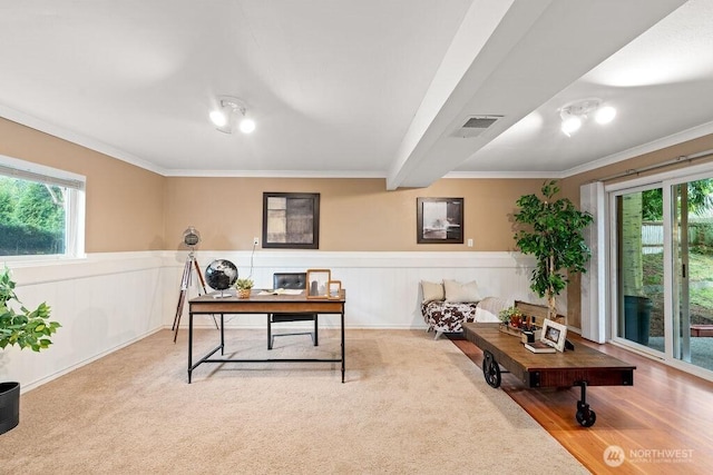 carpeted home office with a wainscoted wall, visible vents, and ornamental molding