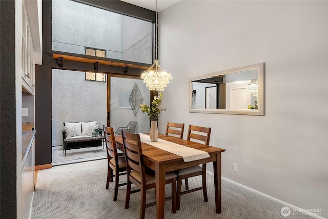 carpeted dining space with baseboards and a high ceiling