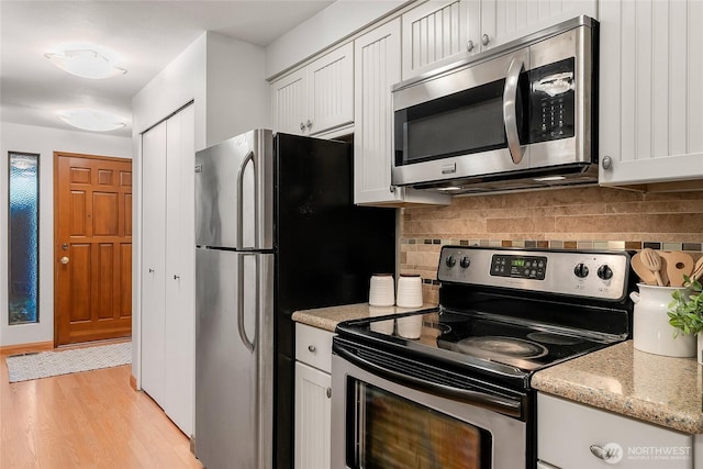 kitchen with light wood-type flooring, stainless steel appliances, backsplash, and white cabinets