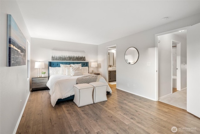 bedroom featuring ensuite bath, baseboards, and wood finished floors