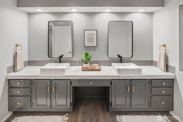 bathroom featuring a sink, baseboards, wood finished floors, and double vanity