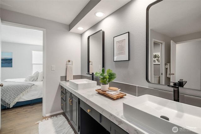 ensuite bathroom with a sink, double vanity, wood finished floors, and ensuite bathroom