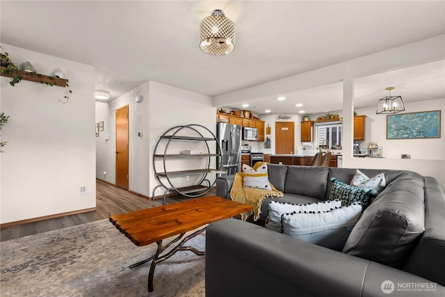 living room featuring recessed lighting, light wood-type flooring, baseboards, and an inviting chandelier