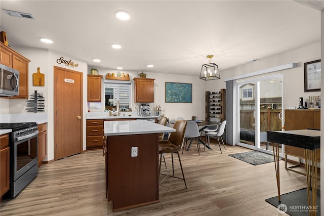 kitchen featuring a breakfast bar area, visible vents, light wood finished floors, and stainless steel appliances