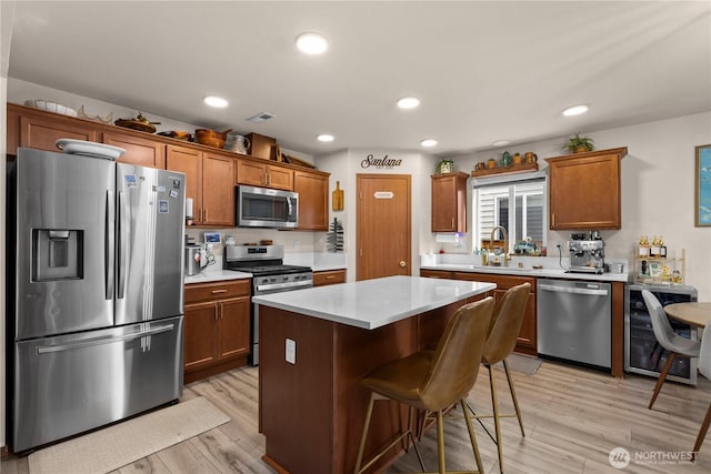 kitchen with beverage cooler, a breakfast bar, light countertops, light wood-style flooring, and appliances with stainless steel finishes