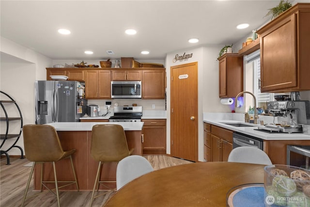 kitchen featuring a center island, light countertops, brown cabinetry, stainless steel appliances, and a sink