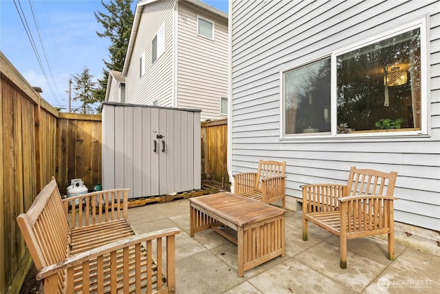 view of patio featuring an outdoor living space, a storage unit, an outbuilding, and a fenced backyard