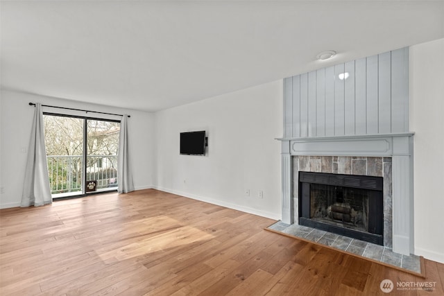 unfurnished living room with hardwood / wood-style flooring, a fireplace, and baseboards