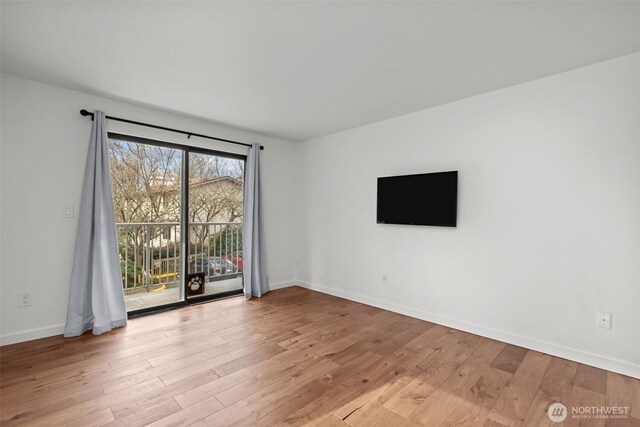 spare room with baseboards and wood finished floors