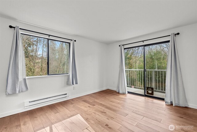 empty room featuring a baseboard radiator, baseboards, light wood-style floors, and a healthy amount of sunlight