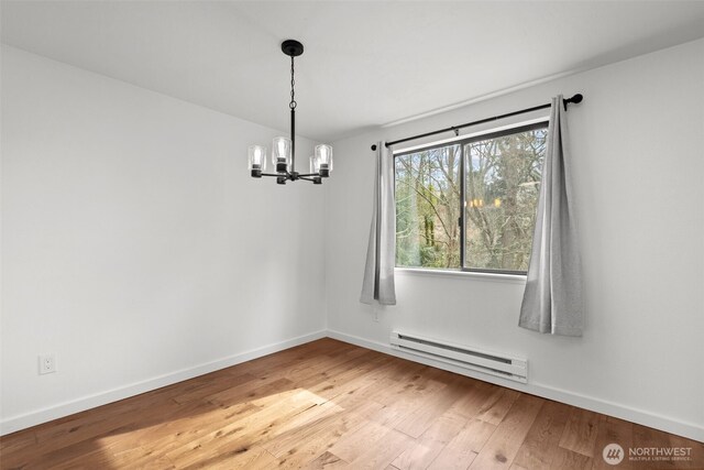 unfurnished dining area with a baseboard heating unit, baseboards, hardwood / wood-style floors, and a chandelier