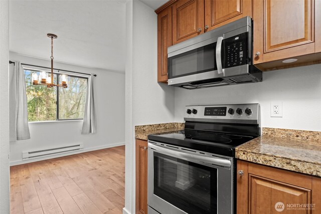 kitchen with light wood finished floors, baseboard heating, brown cabinets, and stainless steel appliances