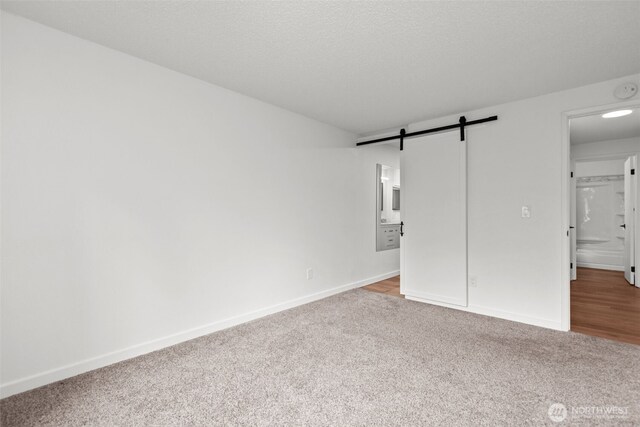 spare room with a barn door, baseboards, and carpet floors