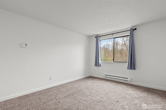 empty room with a baseboard heating unit, baseboards, a textured ceiling, and carpet flooring