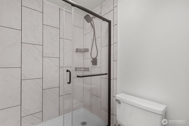 bathroom featuring a shower stall and toilet