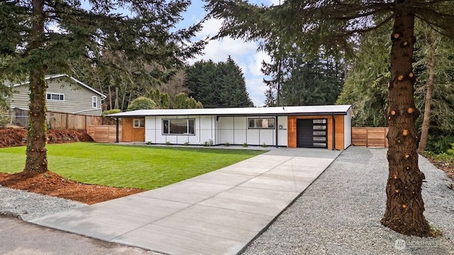 view of front of home featuring a front lawn, fence, board and batten siding, concrete driveway, and a garage