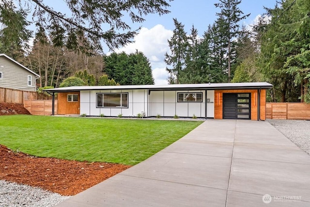 view of front of house featuring board and batten siding, a front lawn, fence, driveway, and an attached garage