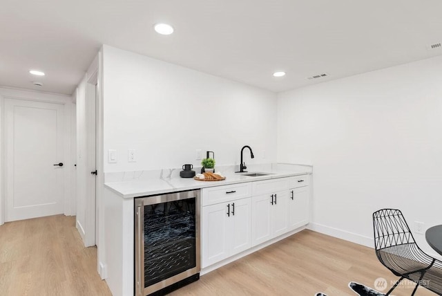 bar featuring light wood finished floors, visible vents, wine cooler, recessed lighting, and a sink