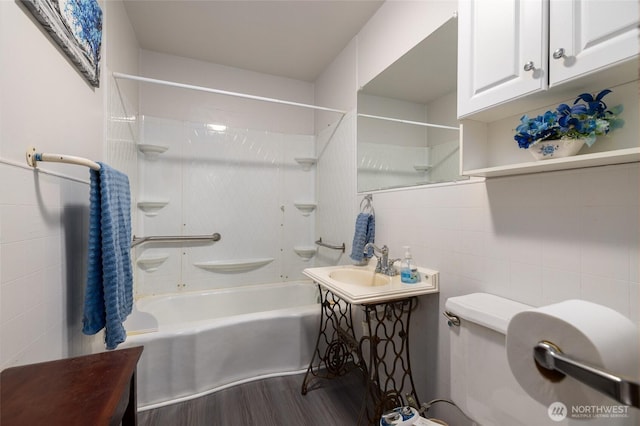 bathroom with tub / shower combination, toilet, tile walls, and wood finished floors