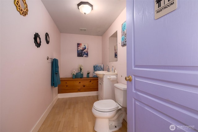 bathroom featuring vanity, toilet, baseboards, visible vents, and wood finished floors