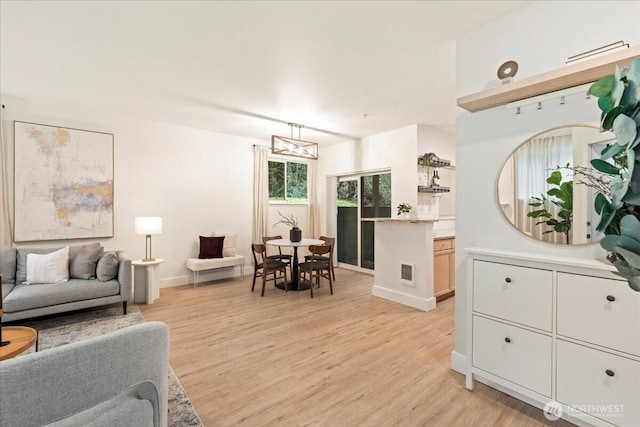 living area featuring light wood-style flooring, baseboards, and visible vents