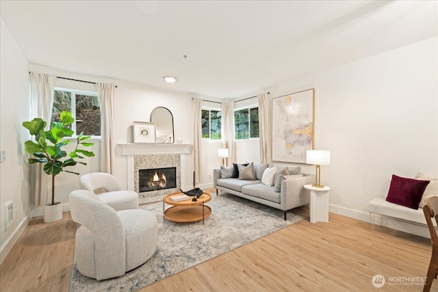 living room with a healthy amount of sunlight, a fireplace, baseboards, and wood finished floors