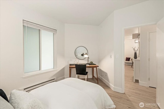 bedroom with a baseboard radiator, baseboards, and light wood-style flooring