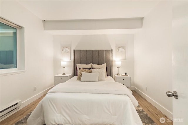 bedroom featuring light wood-style flooring, baseboards, and a baseboard radiator