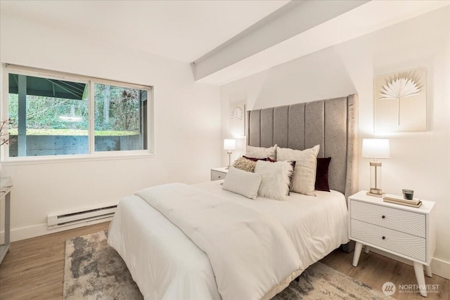 bedroom featuring a baseboard radiator, baseboards, and wood finished floors