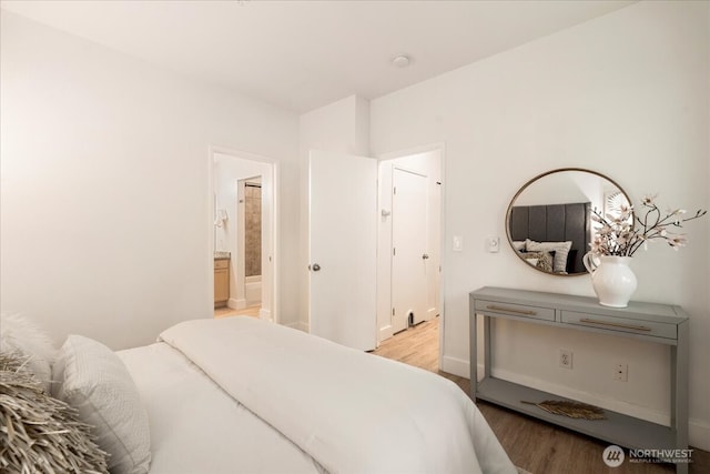 bedroom featuring light wood finished floors and ensuite bathroom