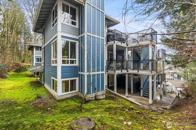 rear view of house with stairway, a yard, and board and batten siding