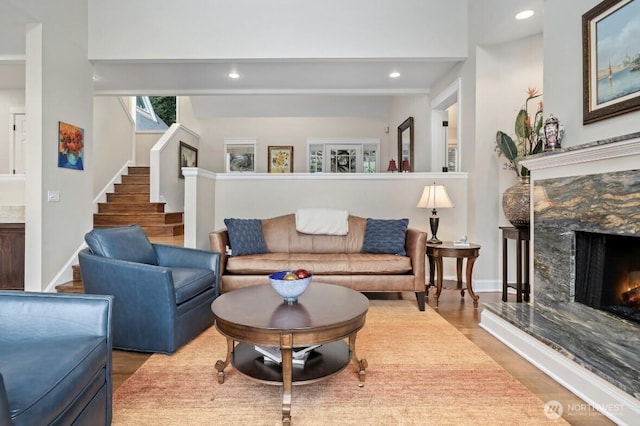 living area featuring wood finished floors, baseboards, a premium fireplace, recessed lighting, and stairs