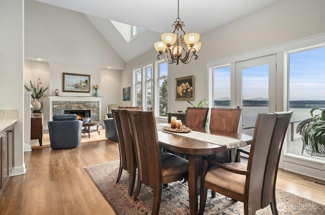 dining area with wood finished floors, visible vents, a chandelier, and a lit fireplace