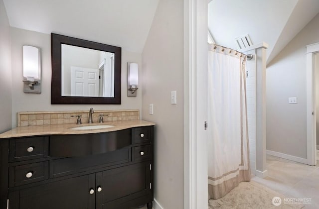 bathroom with tile patterned flooring, vanity, baseboards, and vaulted ceiling