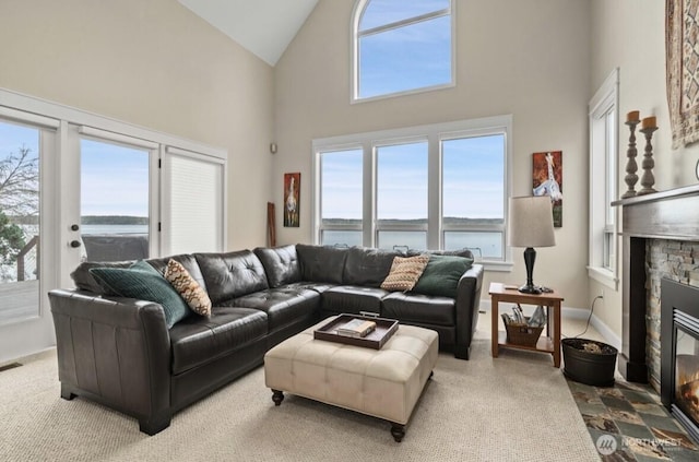 living room with baseboards, visible vents, high vaulted ceiling, a fireplace, and a water view