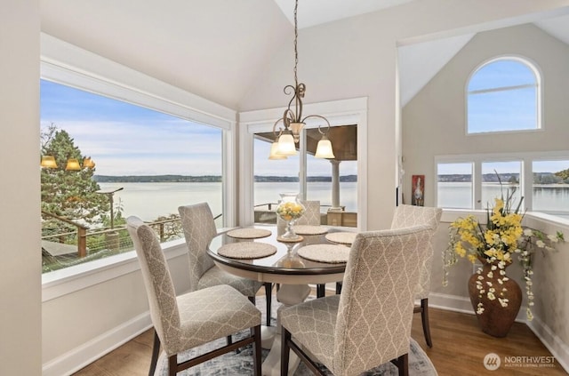 dining area featuring high vaulted ceiling, a water view, baseboards, and wood finished floors