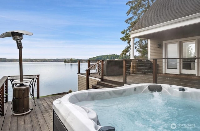 dock area with a hot tub and a deck with water view