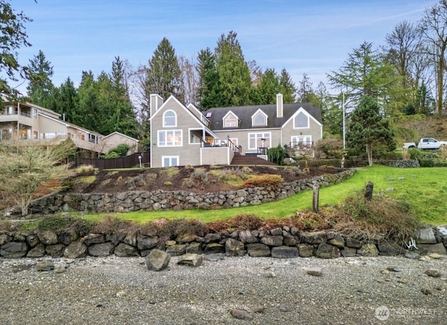 back of property with a chimney, a yard, and fence