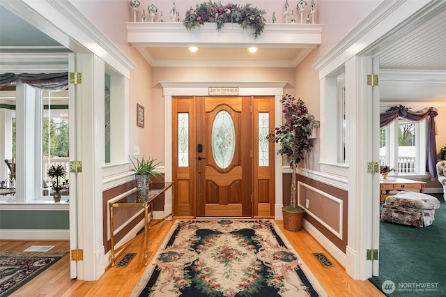 entryway featuring crown molding, wood finished floors, visible vents, and baseboards