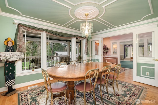 dining space with visible vents, baseboards, wood finished floors, and crown molding