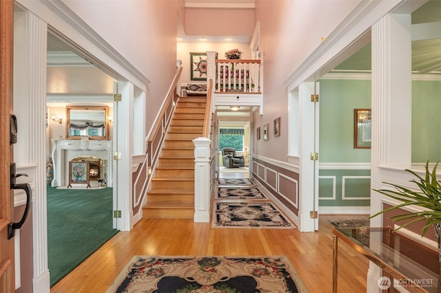 foyer featuring stairs, a decorative wall, light wood-style flooring, and a high ceiling