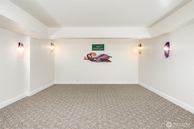 empty room with a tray ceiling, carpet, and baseboards