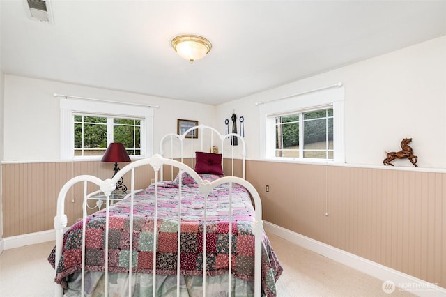 bedroom featuring visible vents, wooden walls, carpet flooring, and wainscoting