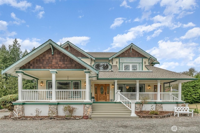 view of front facade featuring roof with shingles and covered porch