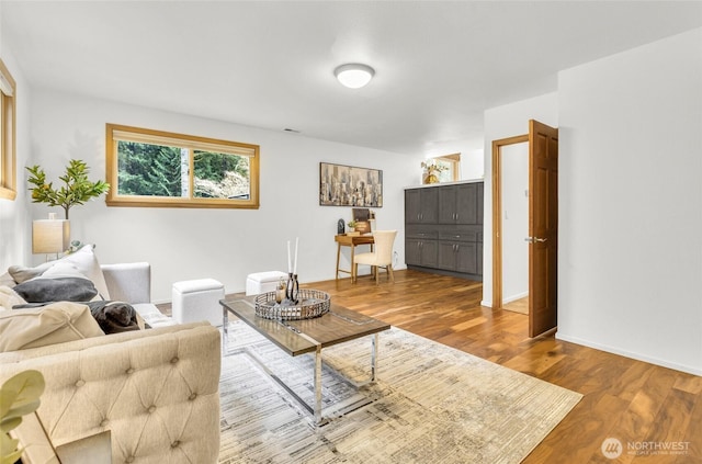 living area with visible vents, baseboards, and wood finished floors