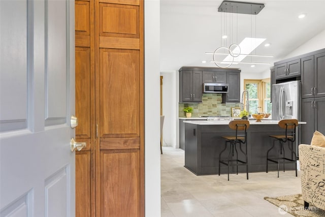 kitchen featuring a kitchen bar, light countertops, decorative backsplash, recessed lighting, and stainless steel appliances