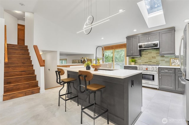 kitchen with tasteful backsplash, appliances with stainless steel finishes, light countertops, and a sink